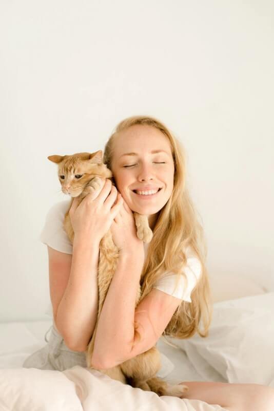 Smiling Blonde Woman Hugging Cat